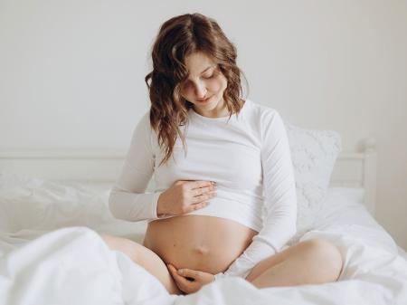 Mulher grávida sentada na cama